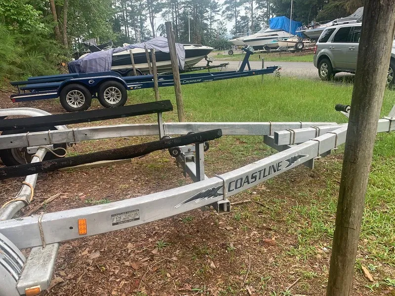 Slide: The Image of Boat trailer in grassy area with parked vehicles and boats in the background. - 19