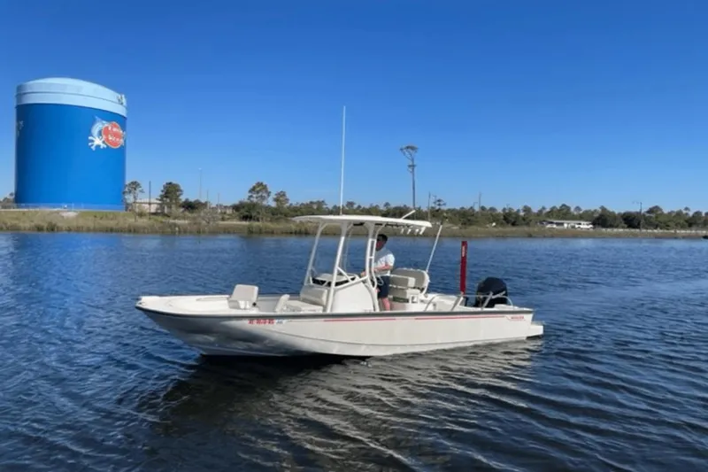Slide: The Image of 2021 Boston Whaler 210 Montauk boat on calm water near a large blue tank. - 9