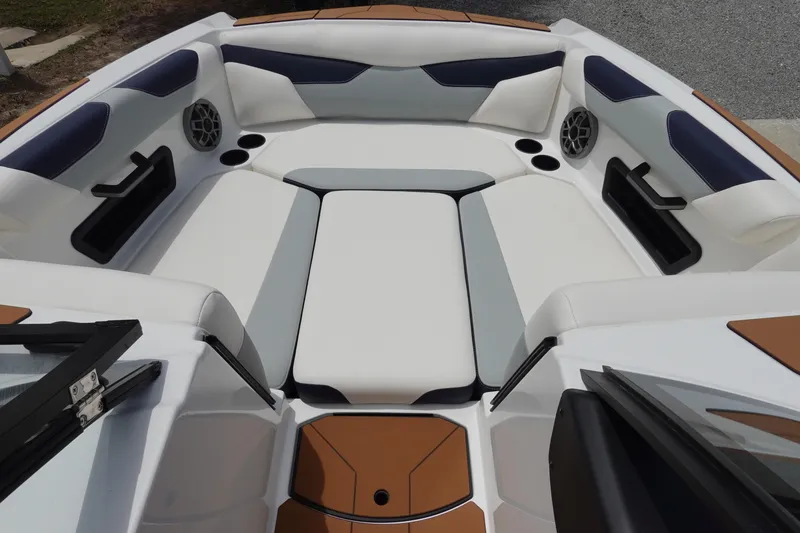 Slide: The Image of 2023 Axis A24 boat interior with white and tan seating, cup holders, and speakers. - 25