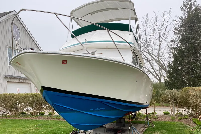 Slide: The Image of 1975 Bertram 28 Flybridge boat on land with blue hull and white upper deck. - 23