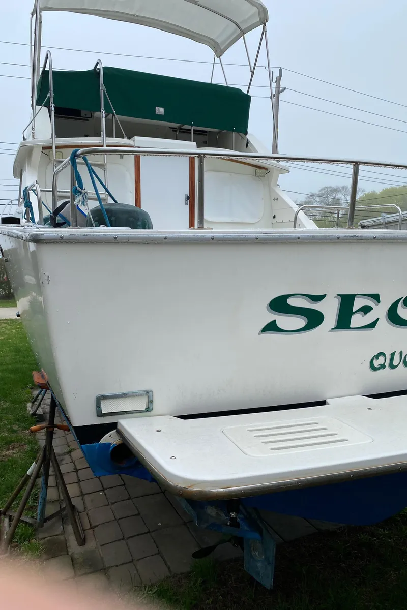 Slide: The Image of 1975 Bertram 28 Flybridge boat with green accents, docked on land. - 24
