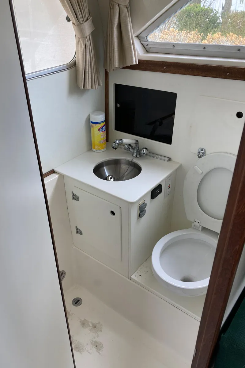 Slide: The Image of 1975 Bertram 28 Flybridge boat bathroom with sink, toilet, and window. - 31