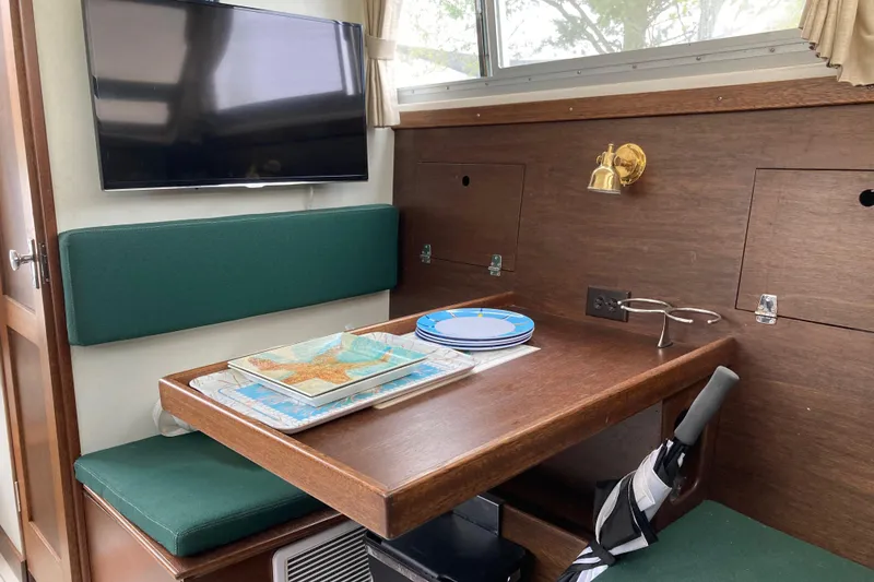 Slide: The Image of 1975 Bertram 28 Flybridge interior dining area with TV and nautical decor. - 32