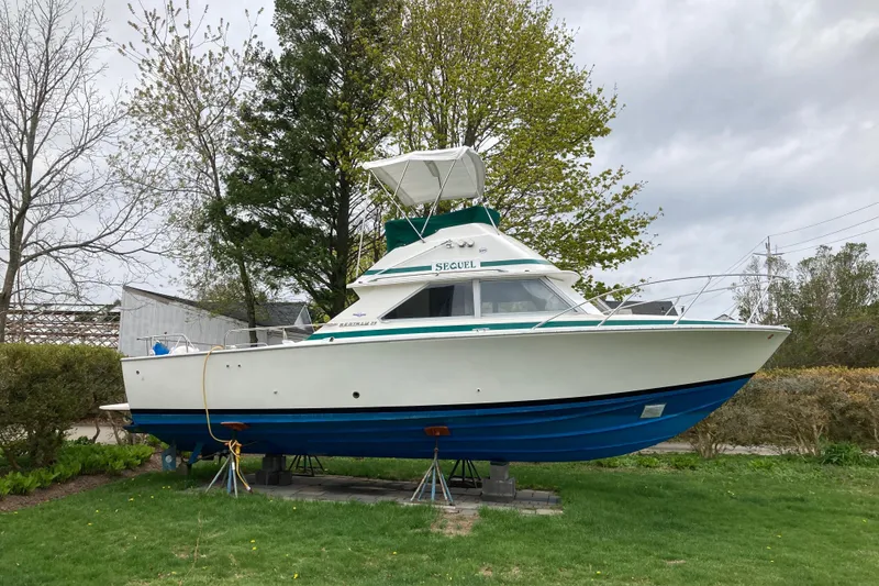 Slide: The Image of 1975 Bertram 28 Flybridge boat on stands in a grassy yard. - 37