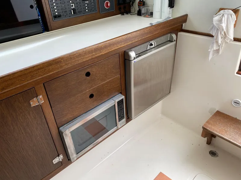 Slide: The Image of 1975 Bertram 28 Flybridge interior with microwave, fridge, and wooden cabinetry. - 7