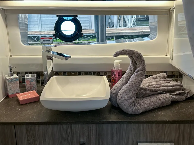 Slide: The Image of 2023 Sea Ray SLX 400 OB bathroom sink with decorative towels and toiletries. - 17