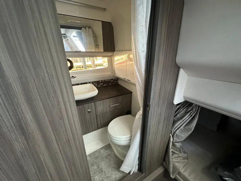 Slide: The Image of 2023 Sea Ray SLX 400 OB bathroom with modern fixtures and wood cabinetry. - 18