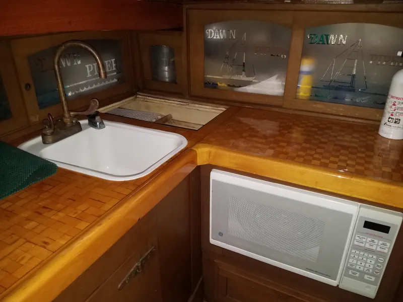 Slide: The Image of 1969 Allied Seabreeze 35 galley with sink, microwave, and wooden cabinetry. - 28