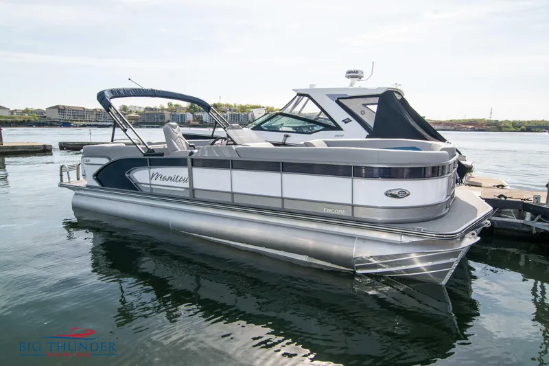 Slide: The Image of 2022 Manitou 25 Encore RF SHP pontoon boat docked on a calm lake. - 0
