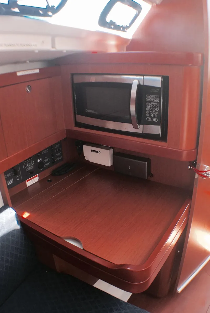 Slide: The Image of 2014 Beneteau Oceanis 34 galley with microwave and wooden cabinetry. - 20