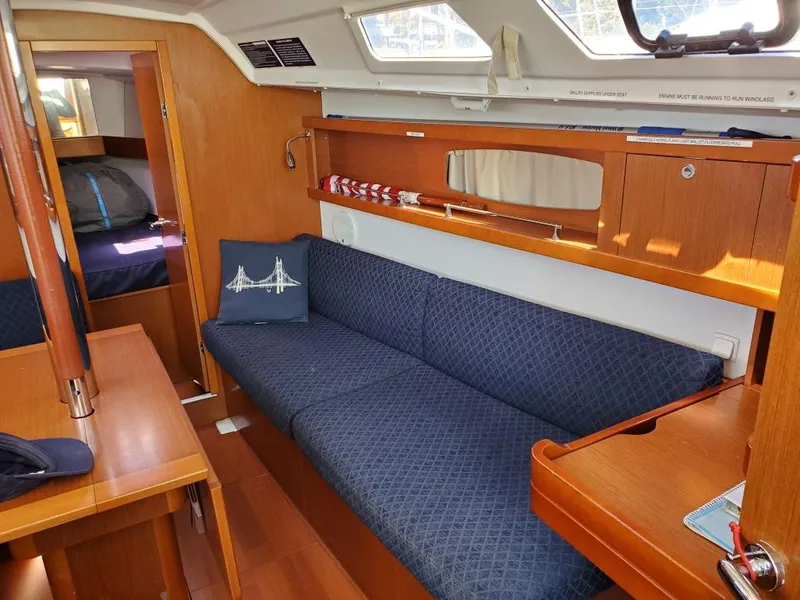 Slide: The Image of Interior of 2014 Beneteau Oceanis 34 sailboat with blue sofa and wooden furnishings. - 24