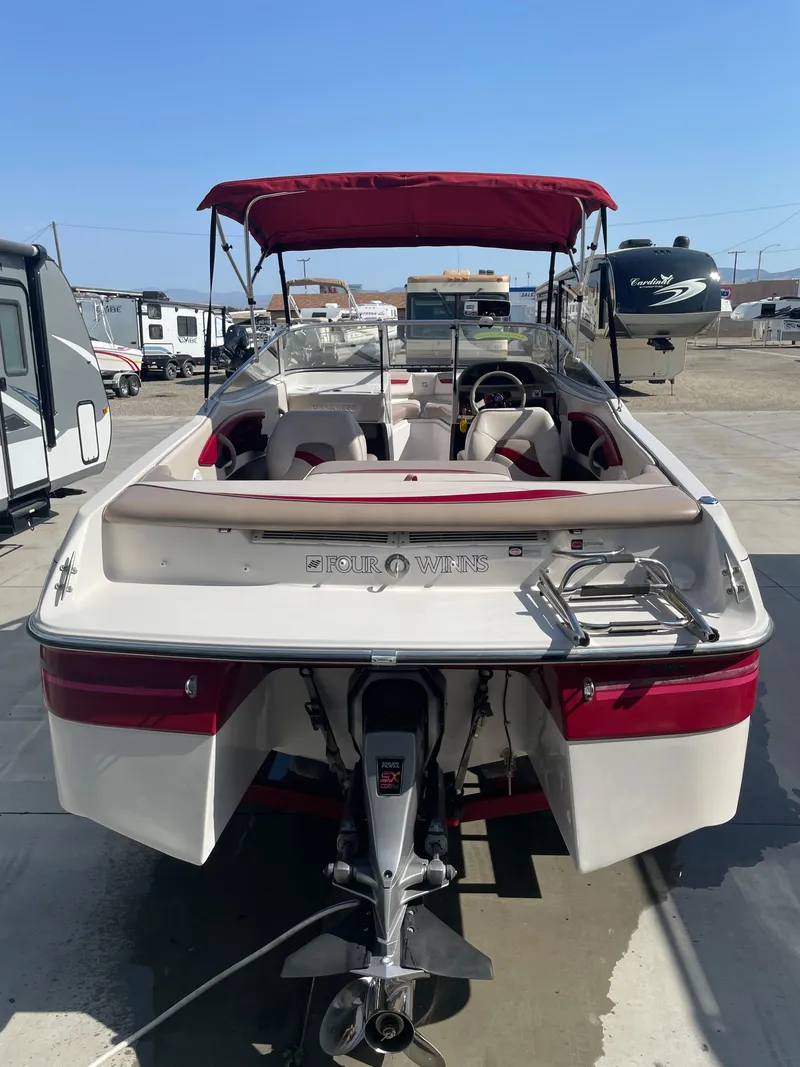 Slide: The Image of 1996 Four Winns 190 Horizon DLX boat with red canopy, parked in a lot. - 2