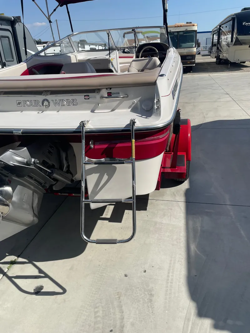 Slide: The Image of 1996 Four Winns 190 Horizon DLX boat with ladder and trailer in a parking area. - 9