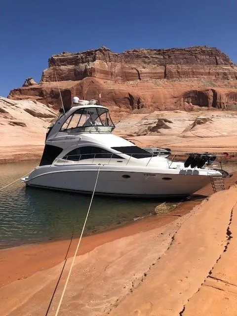 The Image of 2007 Sea Ray 36 Sedan Bridge yacht anchored by red rock cliffs. - 0