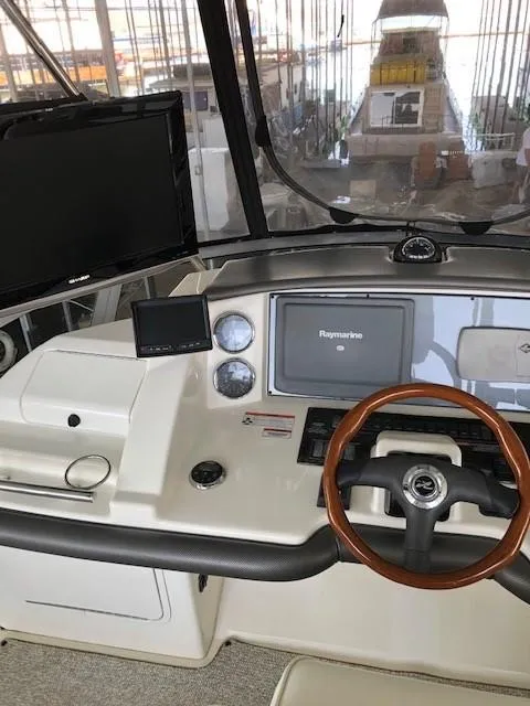 Slide: The Image of 2007 Sea Ray 36 Sedan Bridge helm with Raymarine electronics and wooden steering wheel. - 32