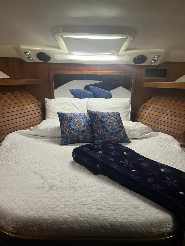 Slide: The Image of 1994 Luhrs 380 Tournament cabin with cozy bed, decorative pillows, and wooden accents. - 17