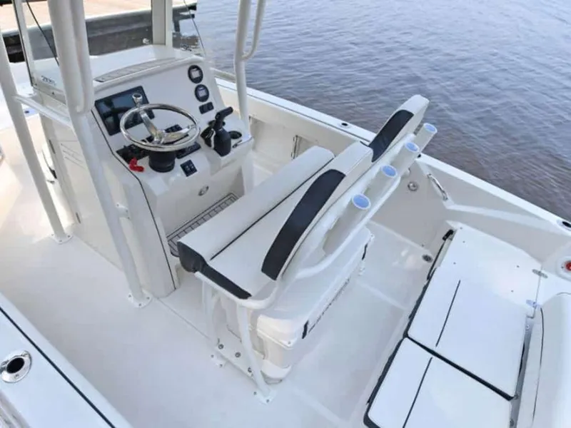Slide: The Image of 2023 Stingray 206cc boat interior with steering console and seating, docked by the water. - 5