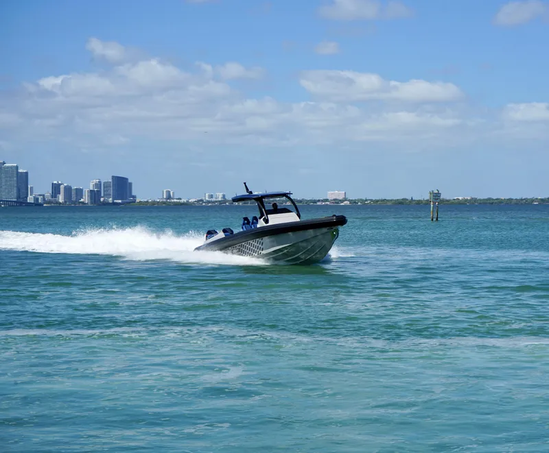 Slide: The Image of 2024 Skipper-BSK 38 speedboat cruising on blue water with city skyline in the background. - 10