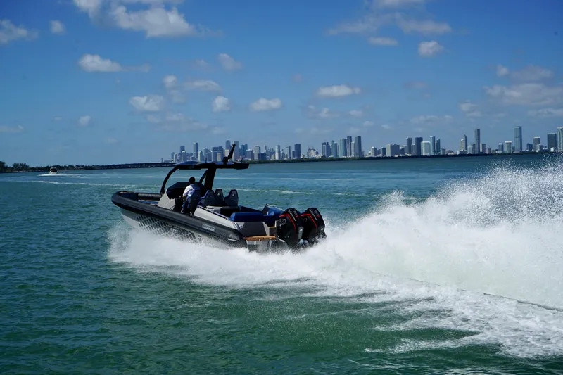 Slide: The Image of 2024 Skipper-BSK 38 boat speeding on water with city skyline in background. - 4