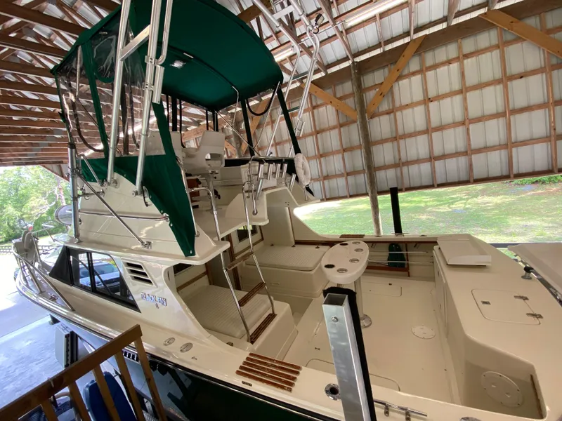 Slide: The Image of 1988 Blackfin 29 Flybridge boat under a wooden shelter, featuring green canopy and spacious deck. - 10