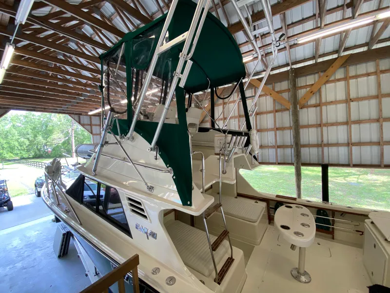 Slide: The Image of 1988 Blackfin 29 Flybridge boat in covered storage, featuring green canopy and spacious deck. - 11