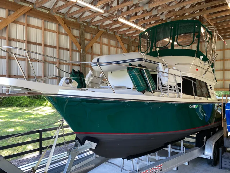 Slide: The Image of 1988 Blackfin 29 Flybridge boat in a wooden boathouse, green hull, on a trailer. - 2