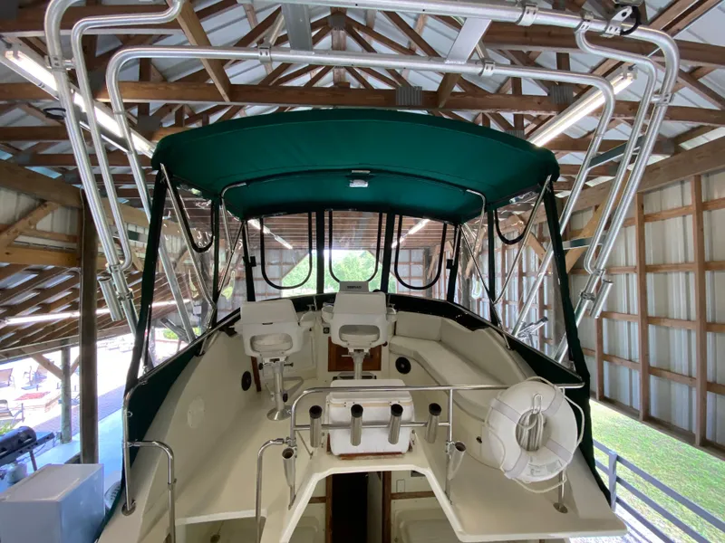 Slide: The Image of 1988 Blackfin 29 Flybridge boat interior with green canopy and seating, stored in a wooden structure. - 34