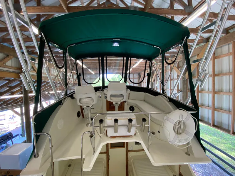 Slide: The Image of 1988 Blackfin 29 Flybridge boat interior with green canopy and seating in a wooden boathouse. - 35
