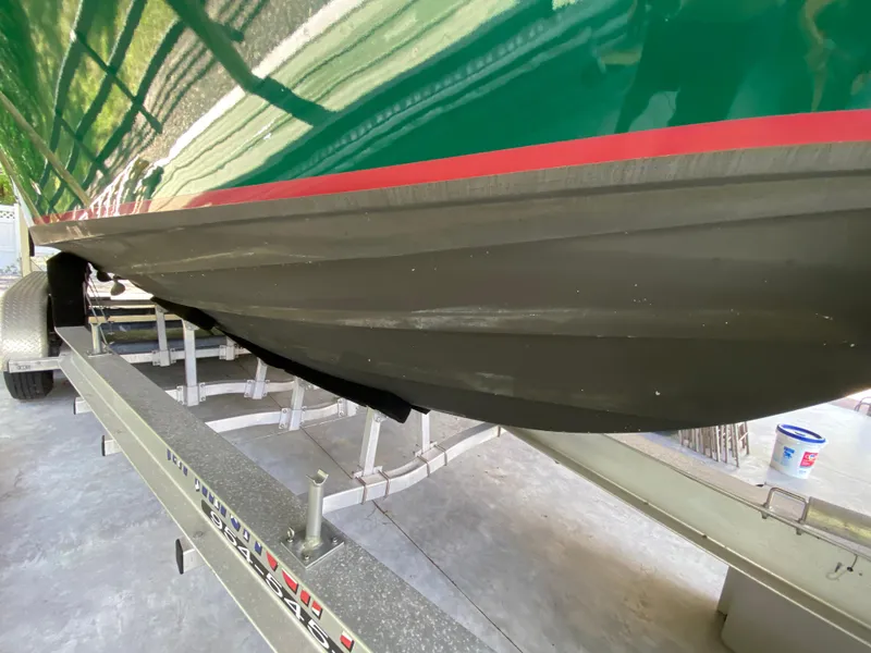 Slide: The Image of 1988 Blackfin 29 Flybridge boat on trailer, green hull with red stripe, viewed from below. - 6