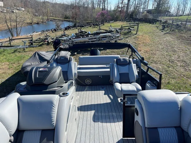 Slide: The Image of 2023 Ranger 2500LS pontoon boat with gray seating, parked near a scenic pond. - 3