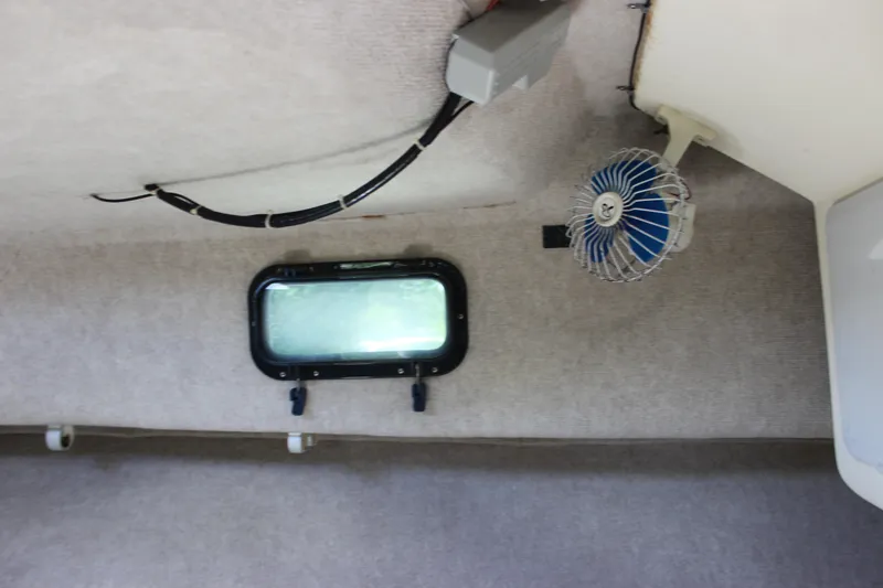 Slide: The Image of Interior cabin of a 1996 Parker 2110 Walkaround boat with a small window and fan. - 28