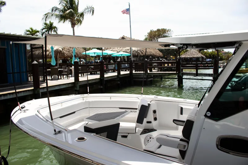 Slide: The Image of 2026 Blackfin 302 CC boat docked near a waterfront restaurant with palm trees. - 9