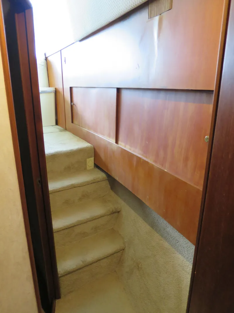 Slide: The Image of Staircase inside a 1999 Ocean Yachts model, featuring wooden paneling and carpeted steps. - 11