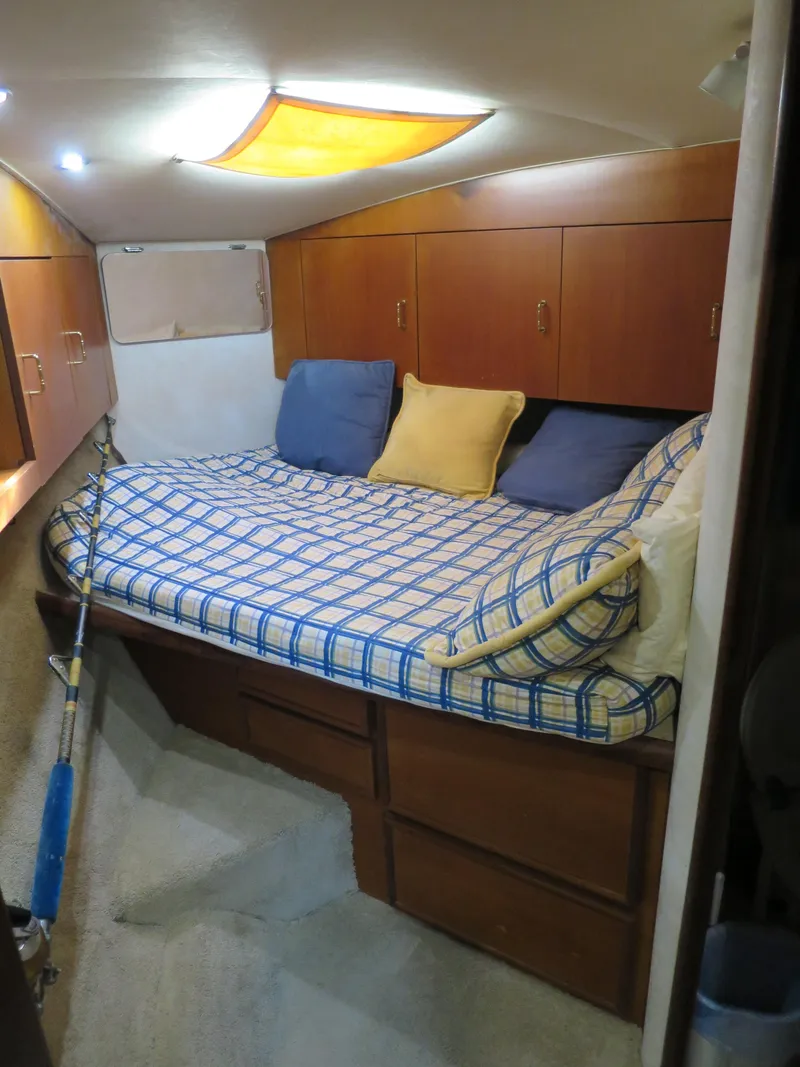 Slide: The Image of Cozy bedroom in a 1999 Ocean Yachts model with wooden cabinets and a checkered bedspread. - 7