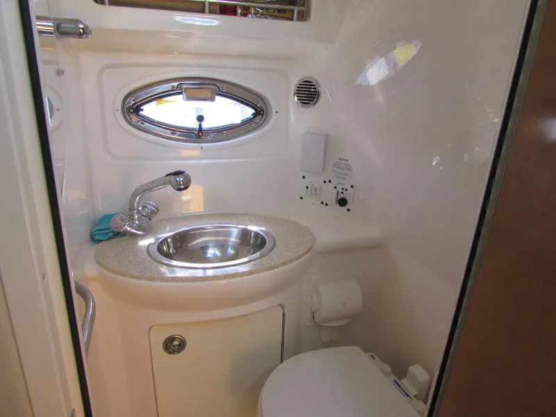 Slide: The Image of Compact bathroom in 2012 Chaparral Signature boat with sink, faucet, and porthole window. - 19