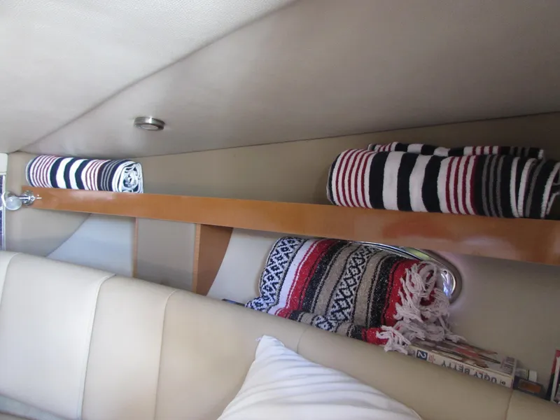Slide: The Image of Interior of 2012 Chaparral Signature boat with rolled striped towels on shelf. - 23