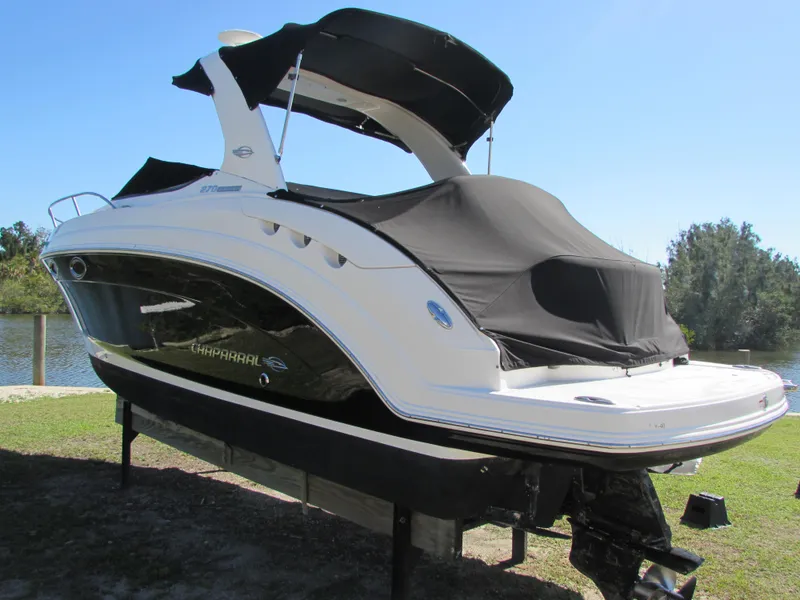 Slide: The Image of 2012 Chaparral Signature boat with black cover on a lift by the water. - 3