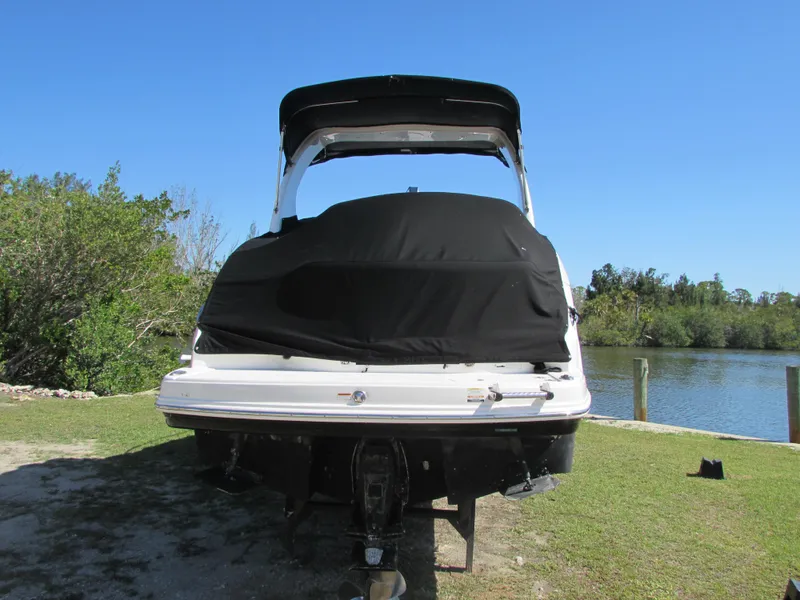 Slide: The Image of 2012 Chaparral Signature boat with black cover, parked near a serene lake. - 5