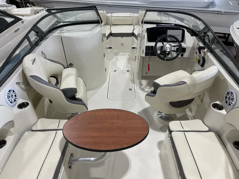 Slide: The Image of 2023 Stingray 211DC boat interior with seating, steering wheel, and wooden table. - 10