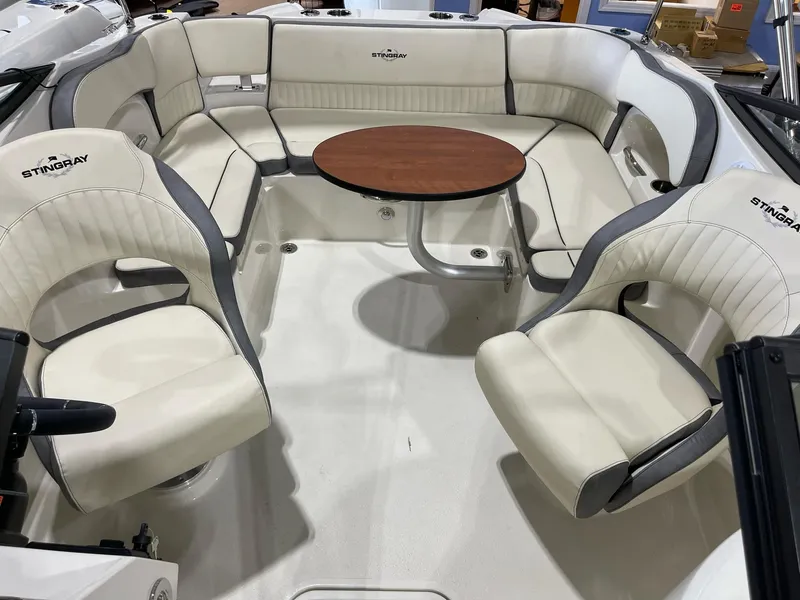 Slide: The Image of 2023 Stingray 211DC boat interior with white seating and a central wooden table. - 11