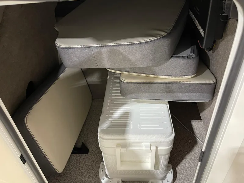 Slide: The Image of Storage compartment in 2023 Stingray 211DC boat with cushions and a white cooler. - 16