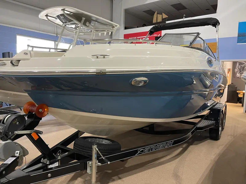 Slide: The Image of 2023 Stingray 211DC boat on trailer in showroom, blue and white exterior. - 7
