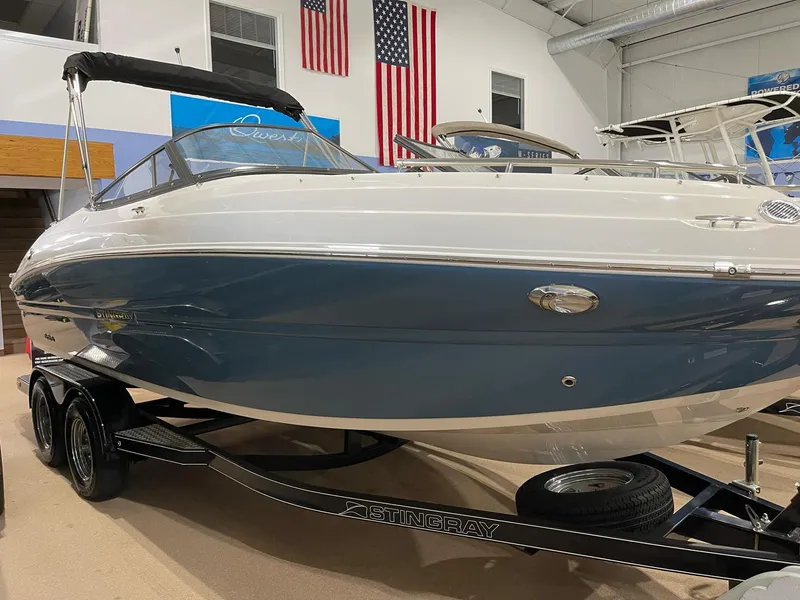Slide: The Image of 2023 Stingray 211DC boat on trailer in showroom with American flags. - 9