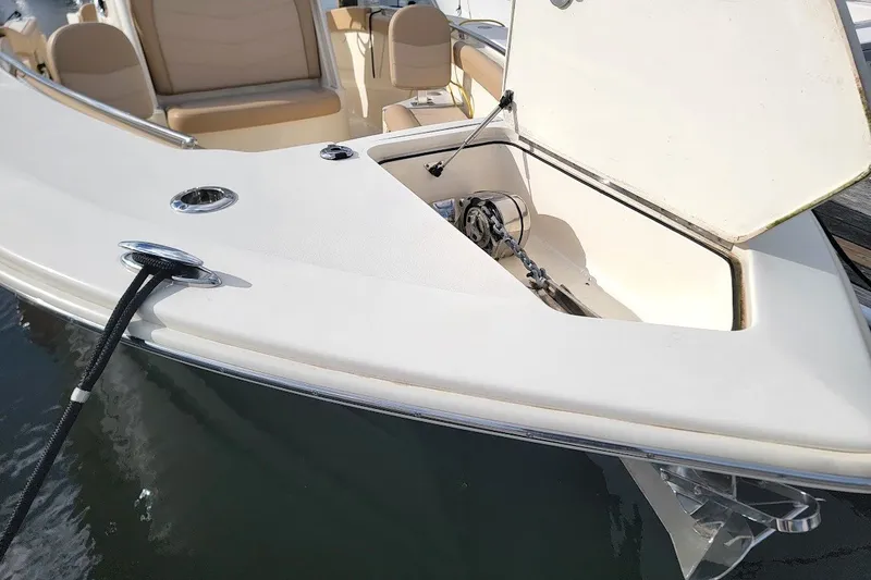 Slide: The Image of 2020 Scout 255 LXF boat with open anchor compartment, docked on water. - 28