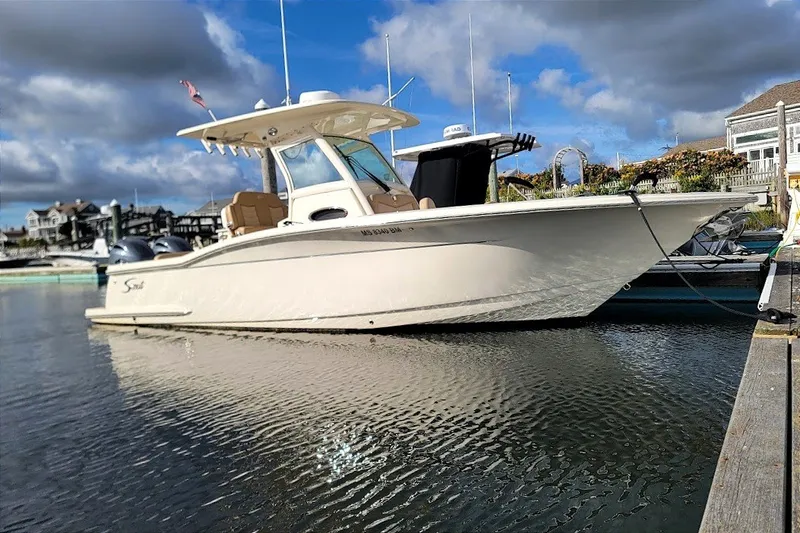 Slide: The Image of 2020 Scout 255 LXF boat docked in a marina under cloudy skies. - 33