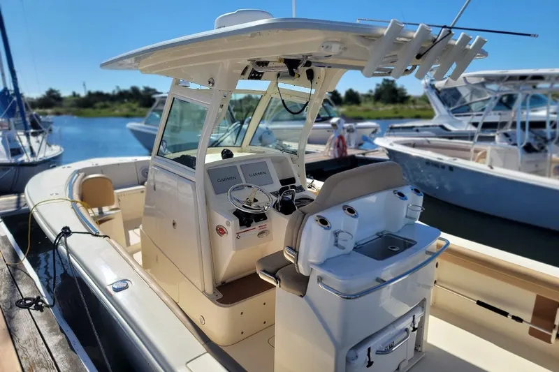 Slide: The Image of 2020 Scout 255 LXF boat docked, featuring Garmin electronics and fishing rod holders. - 1