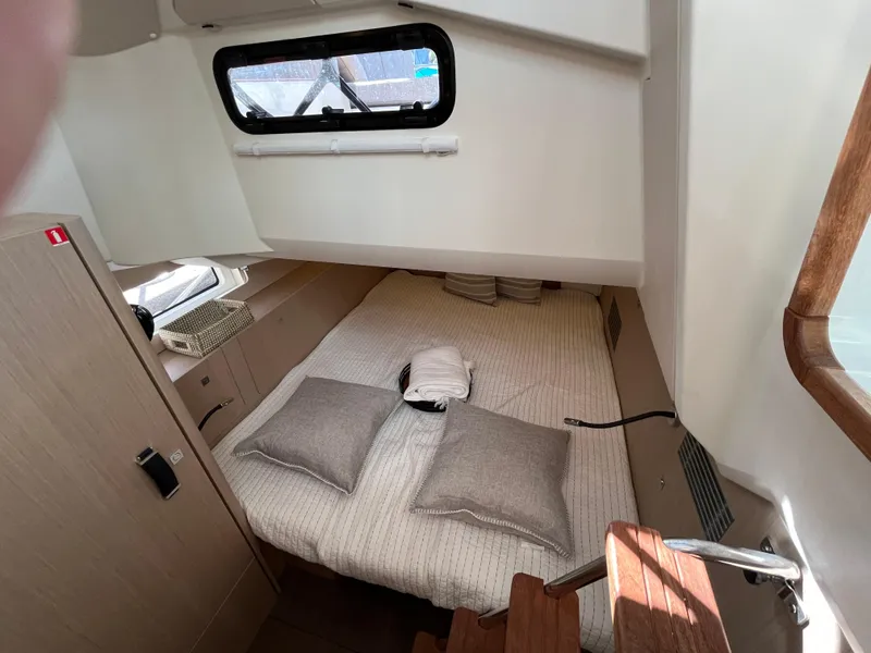 Slide: The Image of 2024 Jeanneau 55 yacht interior cabin with bed, pillows, and window. - 19