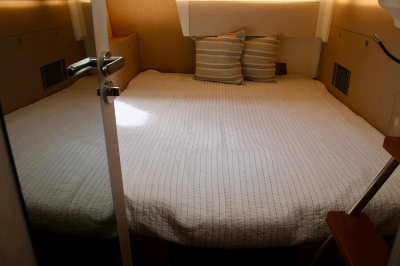 Slide: The Image of 2024 Jeanneau 55 yacht cabin with cozy bed and striped pillows. - 24