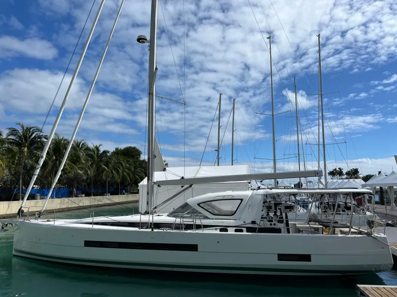 Slide: The Image of 2024 Jeanneau 55 sailboat docked at a marina under a partly cloudy sky. - 6