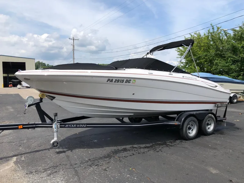 The Image of 2010 Four Winns H220 boat on a trailer in a parking lot. - 0